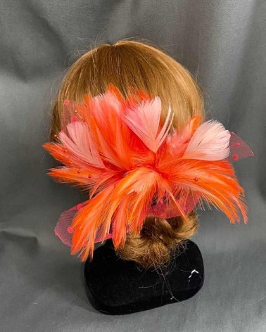 Tocado coral con plumas bicolor y tul plumeti para invitada